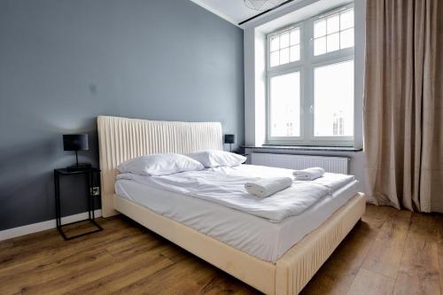 a bedroom with a bed with white sheets and a window at VacationClub - Old Town Apartament 1 in Kłodzko