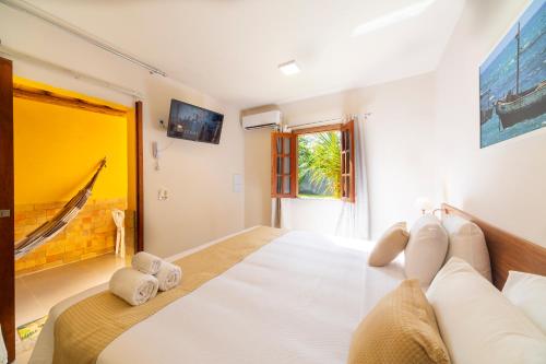 Un dormitorio con una gran cama blanca y una ventana en Pousada Tropicarim en Itacimirim