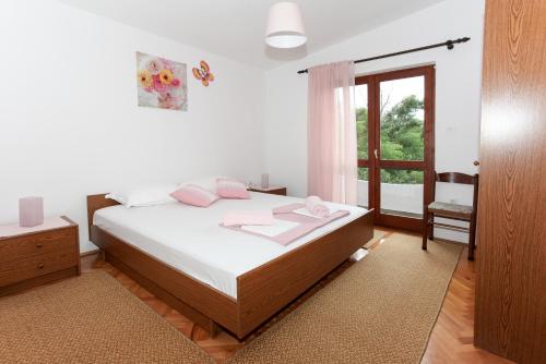 a bedroom with a bed with white sheets and pink pillows at Apartments Spavalo in Pag