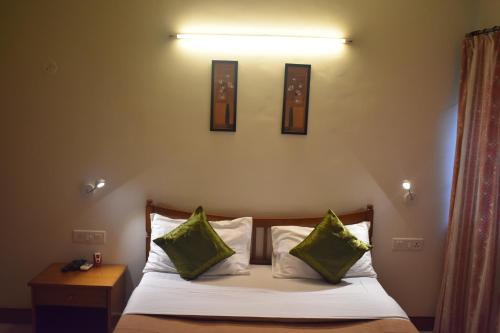 a bedroom with a bed with two green pillows at Ornate Villa in Pune