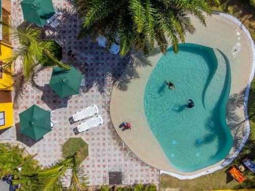 an overhead view of a swimming pool with people and umbrellas at Pousada Tropicarim in Itacimirim