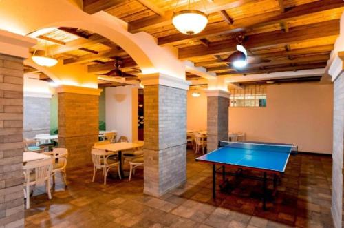 a ping pong table in a room with tables and chairs at Good Stay Premium Studio Apartment 206 in Dabolim