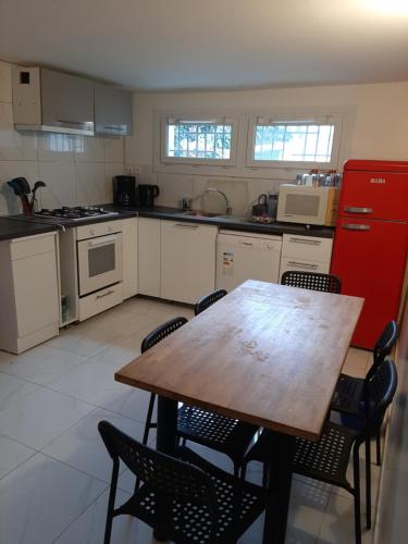 Il comprend une cuisine équipée d'une table en bois et d'un réfrigérateur rouge. dans l'établissement Appartement idéal ouvriers PAS DE TOURISME, à Stains