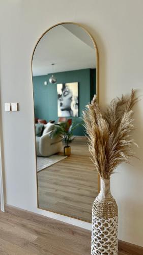 a vase with dry grass in front of a mirror at LUXURY SPACIOUS - 1 BR - SKY GARDENS DIFC - Heart of Trade Centre and Dubai Mall in Dubai