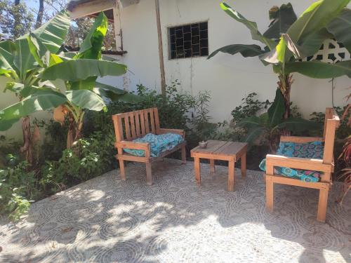 three chairs and a table in front of a building at AKINE TI KASSO piscine in Diembéreng
