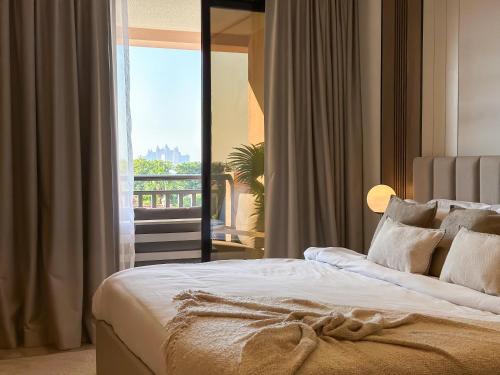 a bedroom with a bed with a view of a balcony at Fabulous 2BR Apartment at 5 Star Resort in Dubai