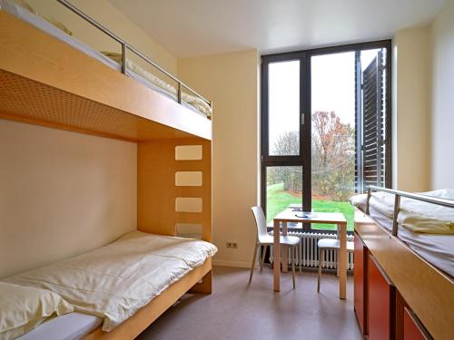 1 Schlafzimmer mit Etagenbetten, einem Tisch und einem Schreibtisch in der Unterkunft Youth Hostel Echternach in Echternach