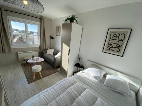 een slaapkamer met een bed en een woonkamer bij Studio cosy à 200m de la plage in Ouistreham