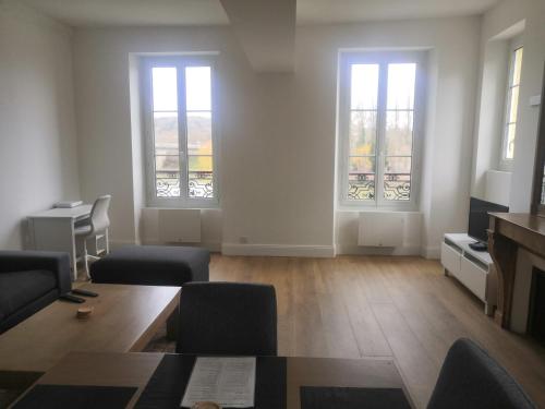 a living room with two windows and a table and chairs at Grand 2P vue seine in Mantes-la-Jolie