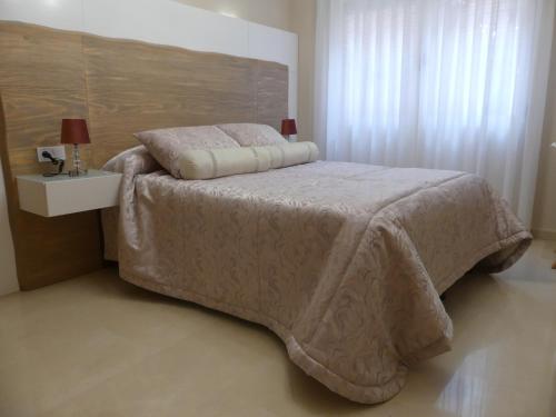 a bedroom with a bed with a white comforter and a table at Casa Felicitas Medina in Medina del Campo