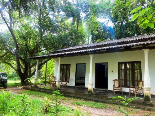 錫吉里亞的住宿－Sigiri Sunrise Villa，森林中带椅子的白色小房子