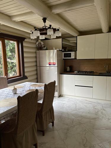 Il comprend une cuisine équipée d'une table, de chaises et d'un réfrigérateur. dans l'établissement Goral cottage in Migovo, à Myhove