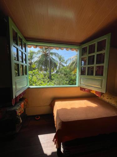 a bedroom with a window with a view of a palm tree at Pousada Hostal das Estrelas in Praia do Frances