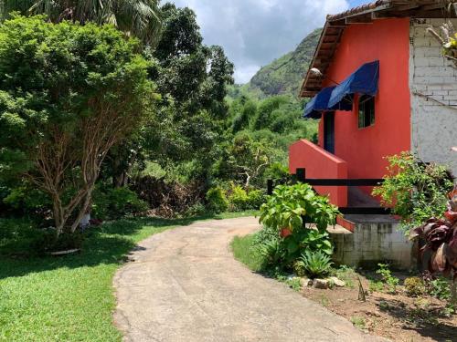 un chemin de terre à côté d'une maison rouge dans l'établissement Pousada dos Viajantes Posse, à Petrópolis