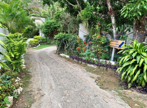 un chemin de terre dans un jardin avec un panneau indiquant la rue dans l'établissement Pousada dos Viajantes Posse, à Petrópolis