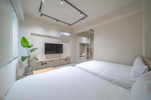 台南的住宿－Times Inn - Tainan，一间白色卧室,配有两张床和一台平面电视