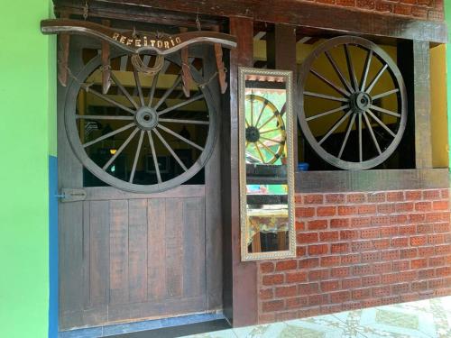 a wooden door with two wheels on a brick wall at Pousada dos Viajantes Posse in Petrópolis