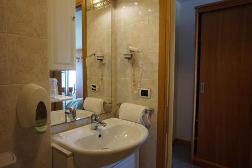 y baño con lavabo y espejo. en Hotel Flora, en Lignano Sabbiadoro