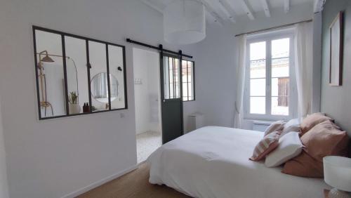 Habitación blanca con cama y espejo en Maison Charmeilles - La suite Pomerol en Fronsac