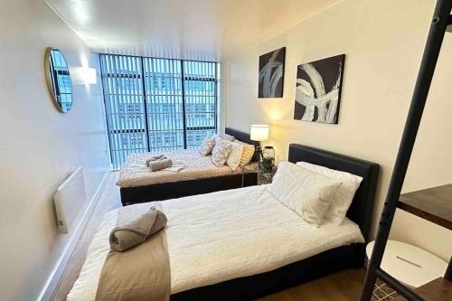 a bedroom with two beds and a window at Urban Chic: 2 Bedroom Apartment in City Centre + FREE Parking in Birmingham