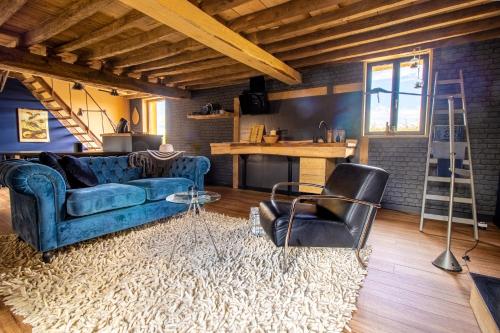 uma sala de estar com um sofá azul e uma escada em Gites Briffaut em Saint-Hilaire-Fontaine