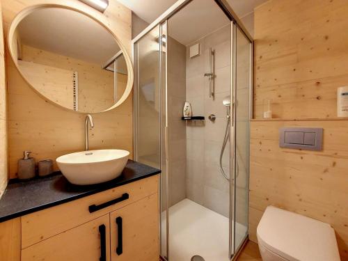ein Bad mit einem Waschbecken und einer Dusche mit einem Spiegel in der Unterkunft La Ruinette - Cosy 2 Bed With Stunning Views in Verbier
