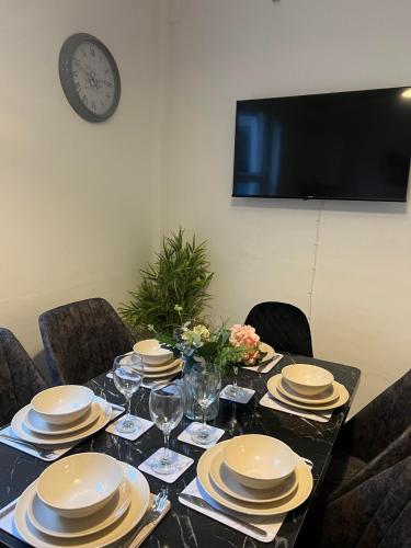uma mesa com pratos e copos e um relógio na parede em Abington Park 5 Bedrooms with en-suite em Spinney Hill