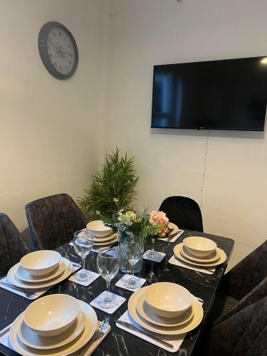 a table with plates and glasses and a clock on the wall at Abington Park 5 Bedrooms with en-suite in Spinney Hill
