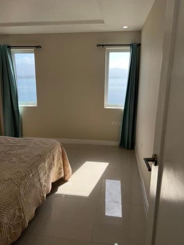 a bedroom with a bed and two windows at Beach access apartment in Portmore