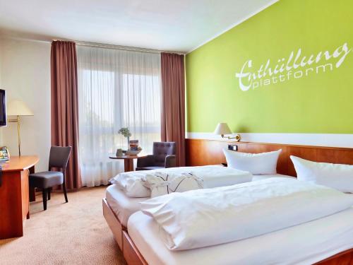 a hotel room with two beds and a desk at Hotel Sportwelt Radeberg in Radeberg