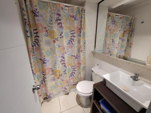 a bathroom with a sink and a toilet and a shower curtain at Depto. Frente a playa y supermercado in Coquimbo