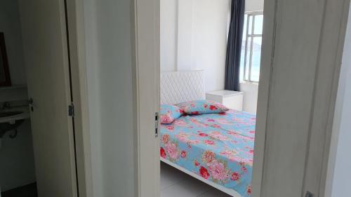 1 dormitorio con cama con sábanas azules y ventana en Apto Temporada Cabo Frio, en Cabo Frío