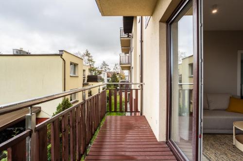 a balcony with a wooden walkway and a couch at Apartament Morska Melodia z balkonem i miejscem do pracy zdalnej in Władysławowo