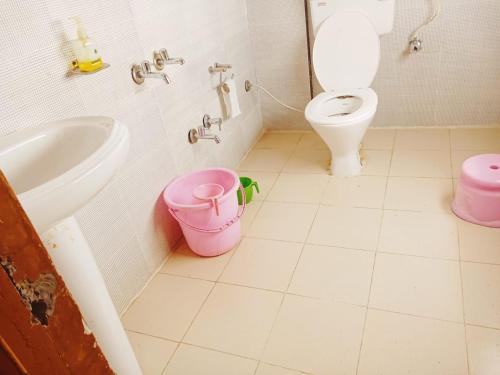 een badkamer met een toilet, een wastafel en een emmer bij Manikarn Resort in Joshimath