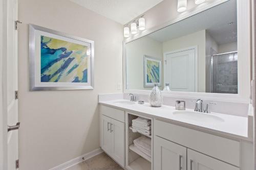 a white bathroom with a sink and a mirror at Serenity Haven - Storey Lake #701 by Shine Villas in Kissimmee