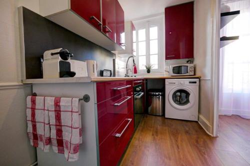 - une cuisine avec des placards rouges et un lave-linge dans l'établissement La Coccinelle - Appartement proche Centre-Ville - Cosy - Mon Groom, à Troyes
