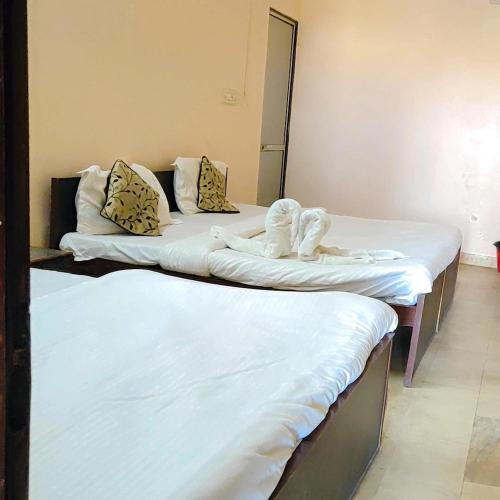 HOTEL CASTLE HOME STAY في جايبور: سريرين في غرفة مع ملاءات بيضاء ومناشف