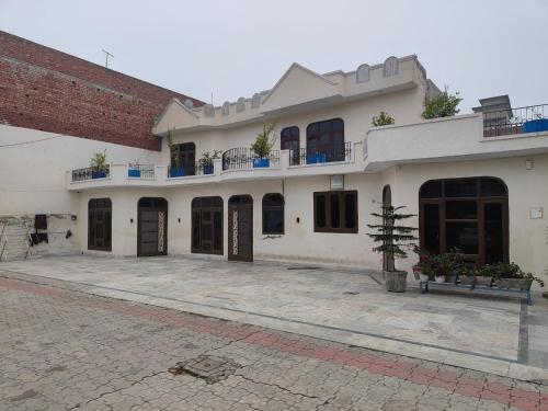 a large white house with a brick building at JS Farm Inn (By The Palm Tree - Family Stay) in Amritsar