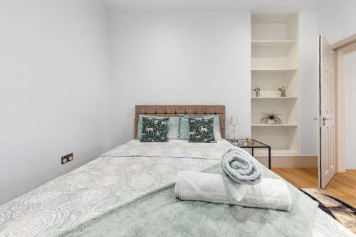 a white bedroom with a large bed and a table at Modern Spacious 1 Bed Flat near Richmond Park in London