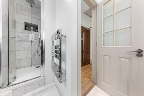 uma casa de banho com um chuveiro e uma porta de vidro em Modern Spacious 1 Bed Flat near Richmond Park em Londres