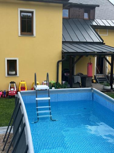 a swimming pool in front of a house at Rodinné apartmány U Šťastných in Černý Dŭl