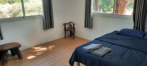 a bedroom with a bed and a chair and windows at โฮมสเตย์แม่ปราณี4 