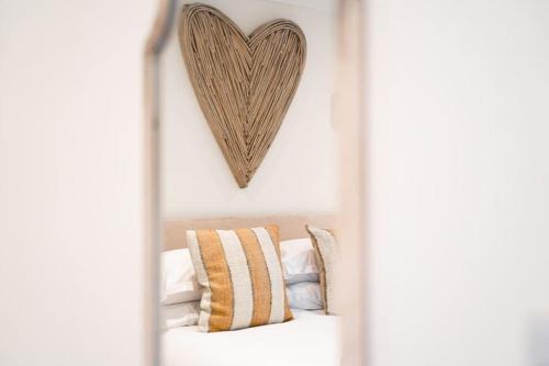 a mirror with a heart hanging above a bed at Hideaway Cottages - Greenacres Estates in Tenby