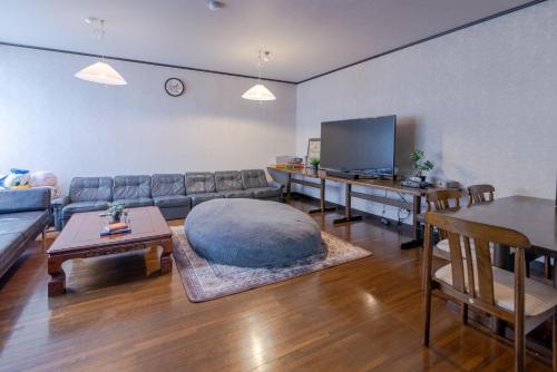 sala de estar con sofá grande y mesa en Sakurasou Lodge, en Nozawa Onsen