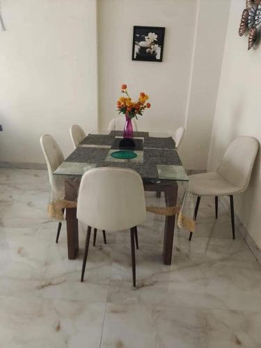 uma mesa de jantar com cadeiras e um vaso com flores em Srpska Chata em Banja Luka