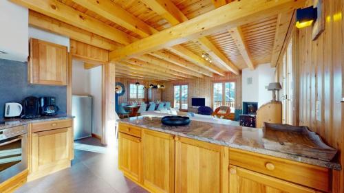 a large kitchen with wooden cabinets and a living room at Narnia SKI IN & SKI OUT chalet 14 pers in Les Collons