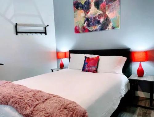 a bedroom with a white bed and a painting on the wall at MetroVista Short Stays in Mott Haven