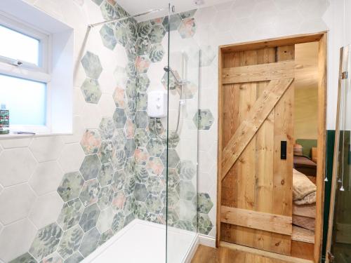 a bathroom with a shower with a sliding door at Goldcrest Hide in Bungay
