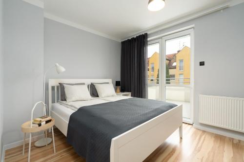 um quarto branco com uma cama e uma grande janela em Dom Sianowska 130 m2, Parking & 3 Balkony Poznań by Renters em Poznań