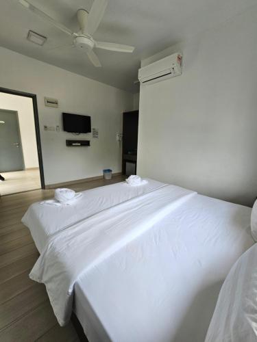 a large white bed in a room with a fan at LiLLA Summer Retreat - Bentong in Kampung Sunjai Gapoi